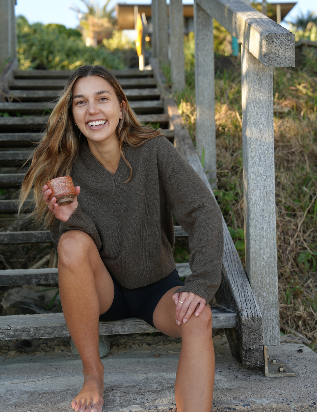 Woman sitting on steps outdoors holding a cup
