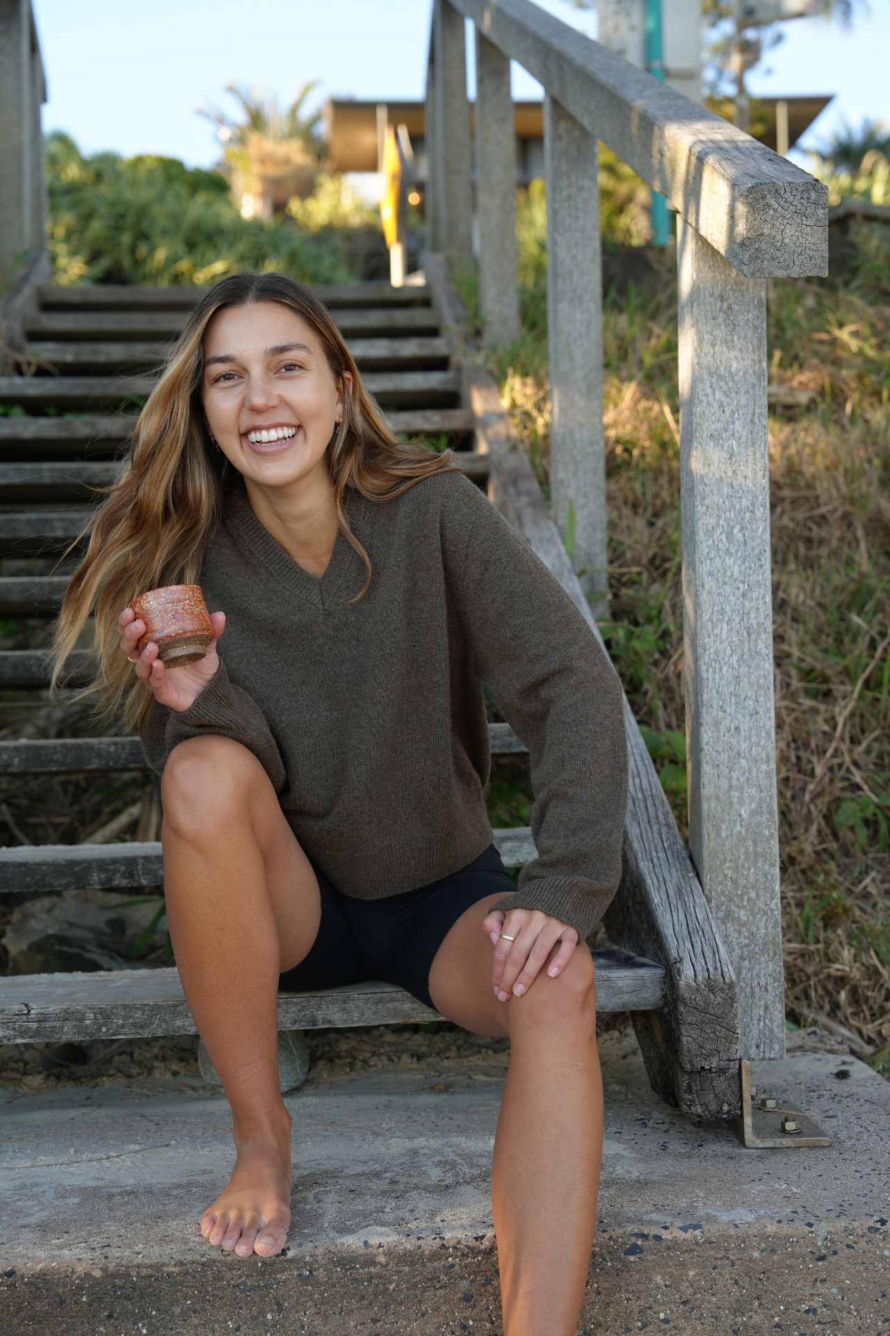 Woman sitting on steps outdoors holding a cup